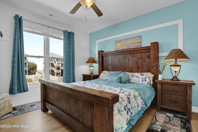 bedroom featuring visible vents, baseboards, wood finished floors, and a ceiling fan