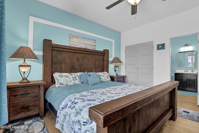 bedroom with connected bathroom, ceiling fan, light wood-style flooring, a closet, and a sink