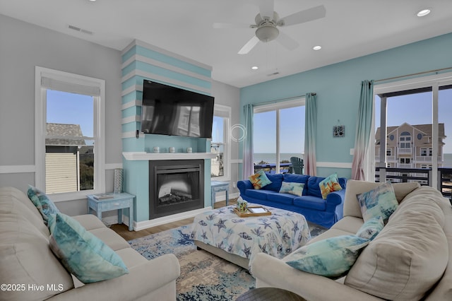 living room featuring visible vents, a healthy amount of sunlight, wood finished floors, and a ceiling fan