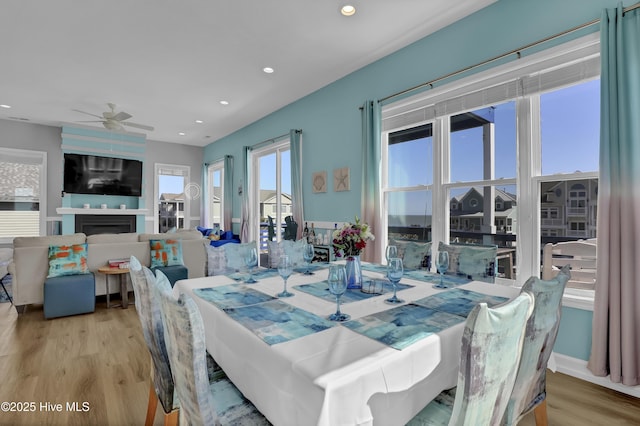 dining space with recessed lighting, a fireplace, wood finished floors, and a ceiling fan