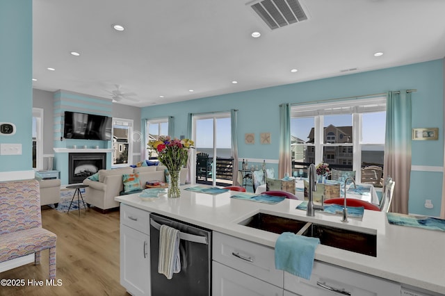 kitchen featuring visible vents, white cabinetry, ceiling fan, a sink, and dishwasher