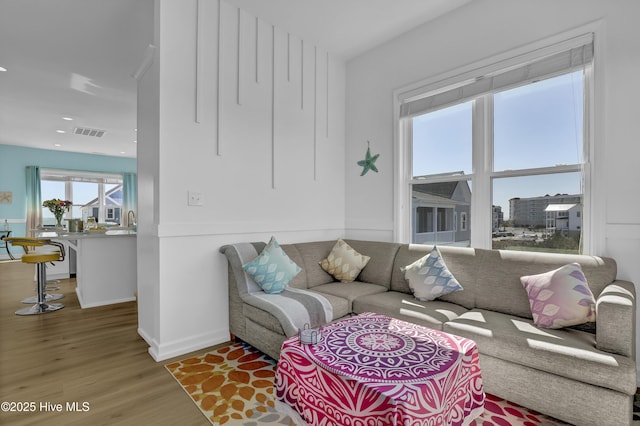 living area featuring recessed lighting, visible vents, baseboards, and wood finished floors