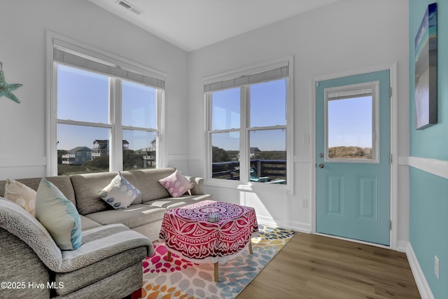 living area with visible vents, wood finished floors, and baseboards