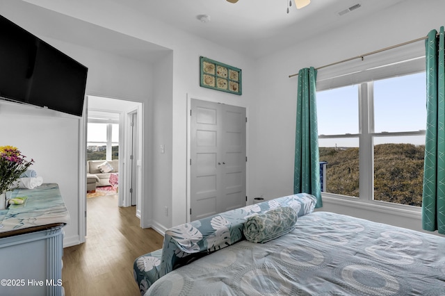 bedroom featuring multiple windows, wood finished floors, visible vents, and baseboards