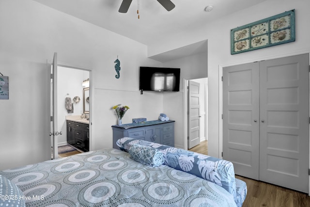 bedroom featuring a closet, ensuite bath, wood finished floors, and a ceiling fan