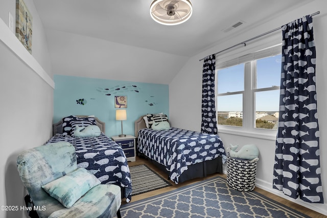 bedroom with visible vents, lofted ceiling, baseboards, and wood finished floors