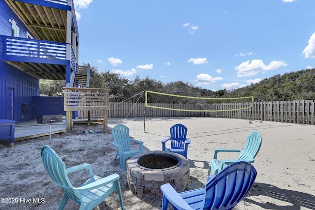 view of patio / terrace with volleyball court, fence, stairs, and an outdoor fire pit