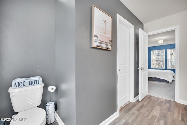 bathroom with wood finished floors, toilet, and baseboards