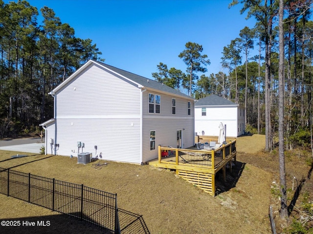 back of house featuring central AC, fence, a deck, and a lawn