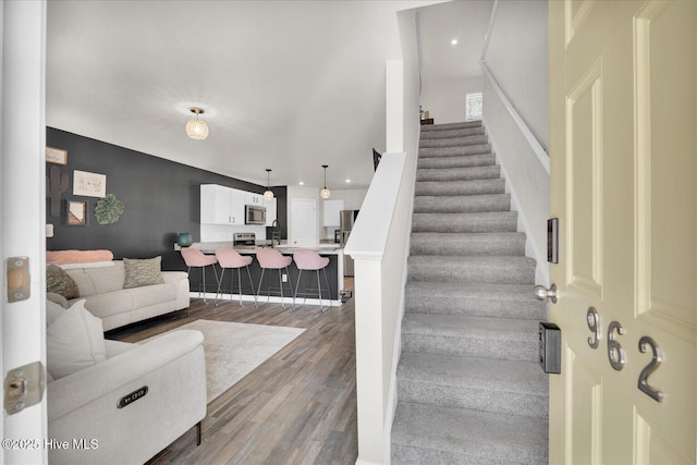 stairway with wood finished floors and recessed lighting