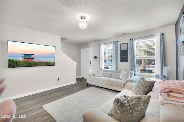 living room with baseboards, visible vents, and wood finished floors