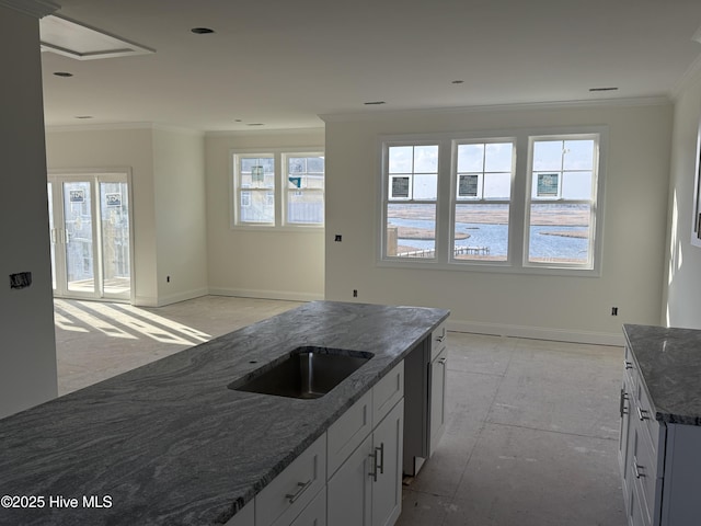 kitchen with baseboards, ornamental molding, dark stone counters, and a wealth of natural light