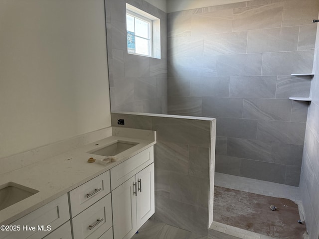 full bathroom with double vanity, walk in shower, and a sink