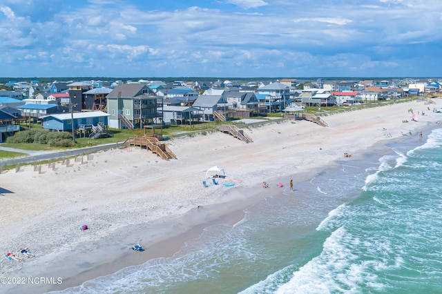 drone / aerial view featuring a water view, a residential view, and a beach view