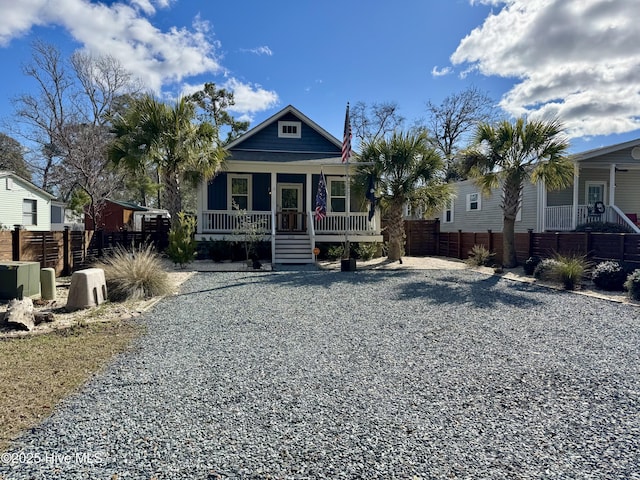 view of front of home featuring covered porch, driveway, and fence