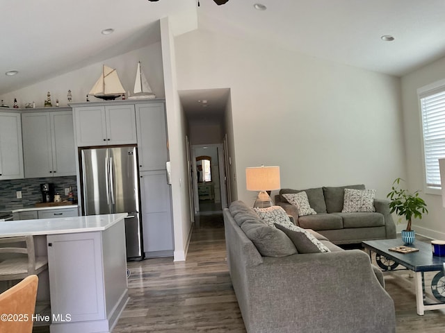 living room with lofted ceiling, ceiling fan, wood finished floors, and baseboards