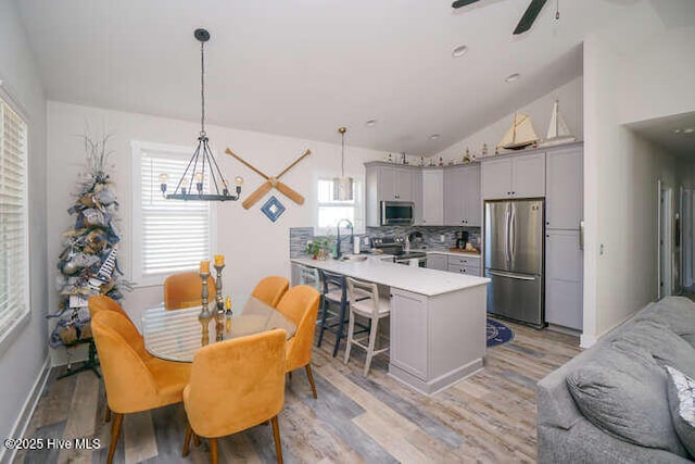 226 NE 76th St, Oak Island, NC 28465 - kitchen with stainless steel appliances, gray cabinetry, a peninsula, light countertops, and light wood-style flooring