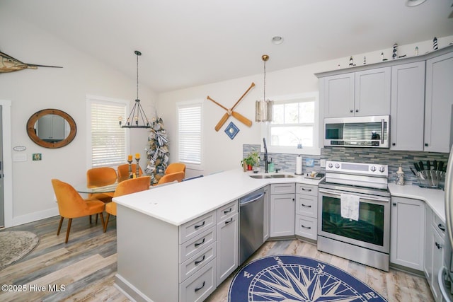 226 NE 76th St, Oak Island, NC 28465 - kitchen with stainless steel appliances, a peninsula, tasteful backsplash, a sink, and light wood finished floors
