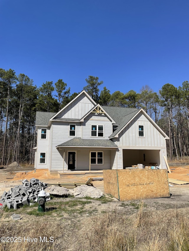 view of front of home featuring board and batten siding, roof with shingles, and a garage