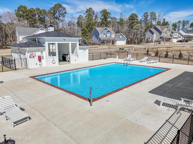 community pool featuring a residential view, fence, and a patio