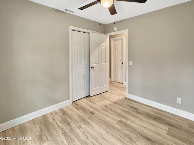 unfurnished bedroom featuring a ceiling fan, baseboards, visible vents, a closet, and light wood-type flooring