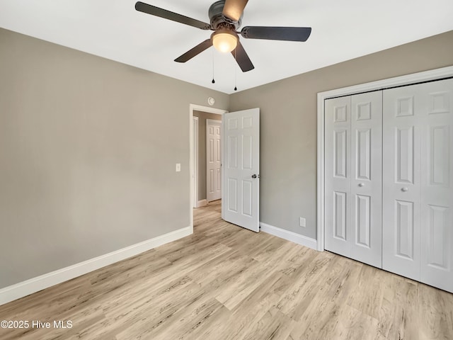 unfurnished bedroom featuring a closet, a ceiling fan, baseboards, and light wood finished floors