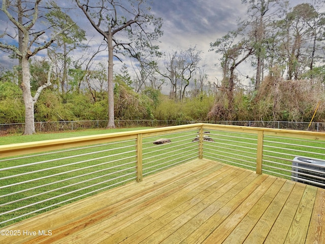 wooden terrace featuring central AC unit, a lawn, and a fenced backyard