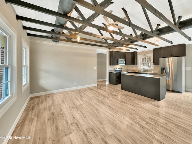 kitchen with light wood-style flooring, a sink, a kitchen island, stainless steel appliances, and light countertops