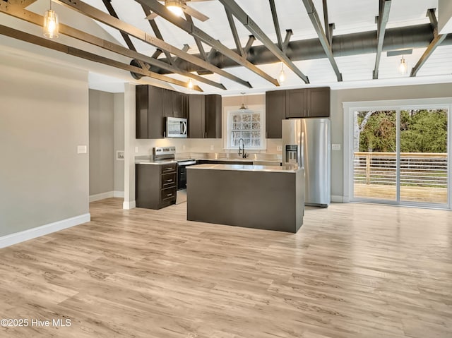 kitchen with light wood-style flooring, decorative light fixtures, appliances with stainless steel finishes, light countertops, and vaulted ceiling with beams