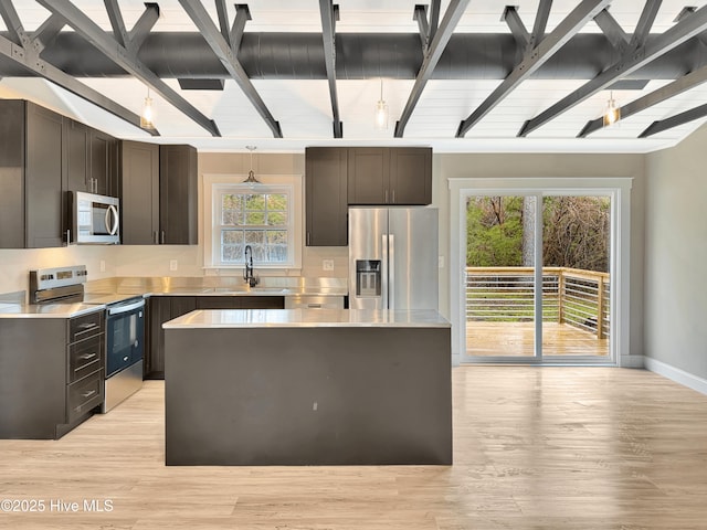 kitchen featuring a center island, stainless steel appliances, light countertops, and a sink