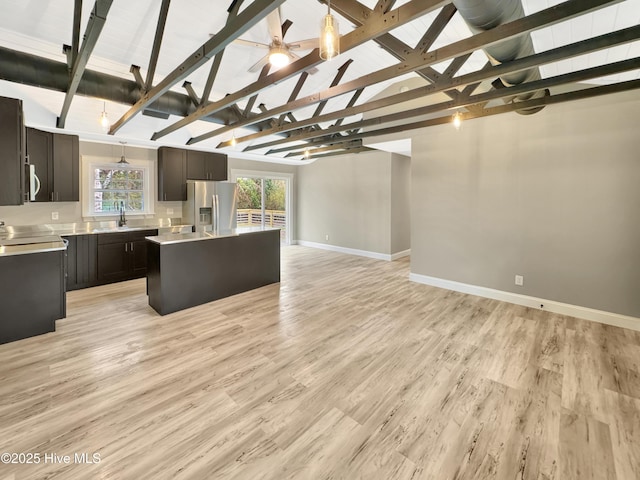 kitchen featuring a ceiling fan, light wood finished floors, light countertops, stainless steel fridge, and open floor plan