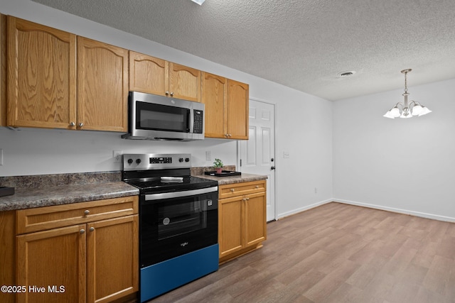 kitchen featuring a textured ceiling, black range with electric stovetop, stainless steel microwave, and light wood-style floors