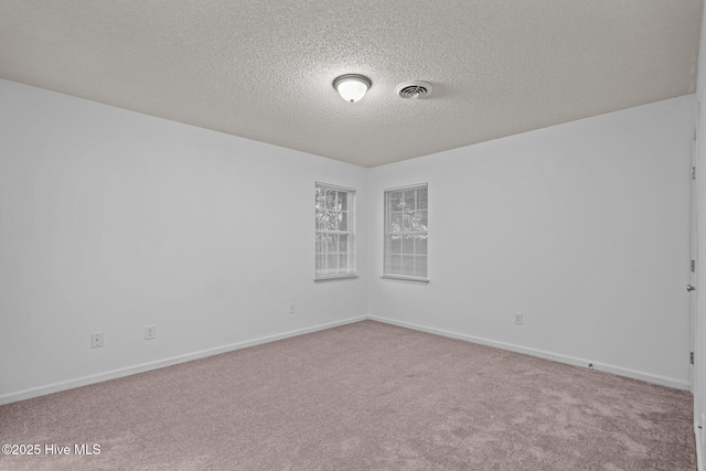 carpeted empty room featuring visible vents, a textured ceiling, and baseboards