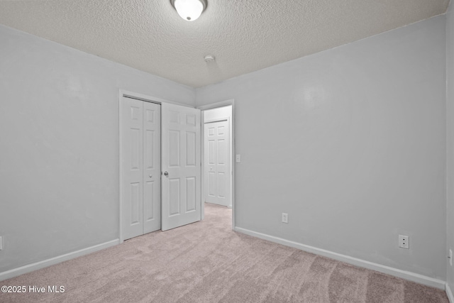 unfurnished bedroom featuring a textured ceiling, a closet, baseboards, and carpet flooring