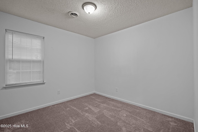 empty room with baseboards, a textured ceiling, visible vents, and carpet flooring