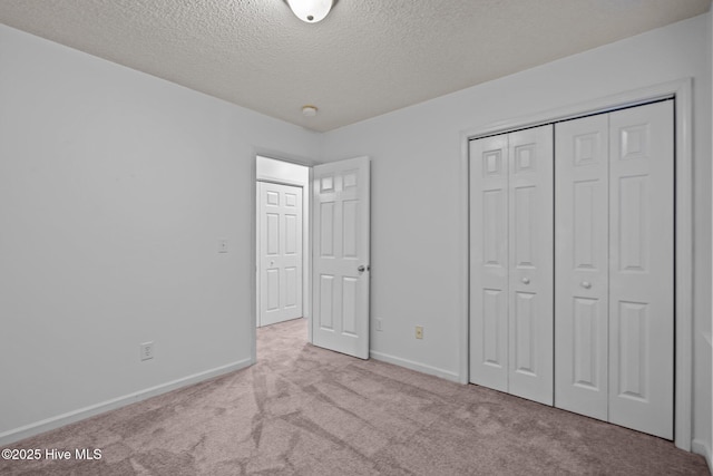 unfurnished bedroom featuring carpet floors, a closet, a textured ceiling, and baseboards