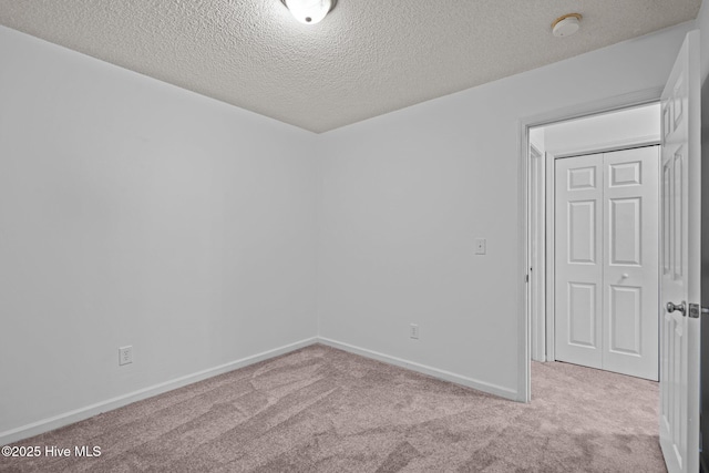 carpeted empty room with a textured ceiling and baseboards