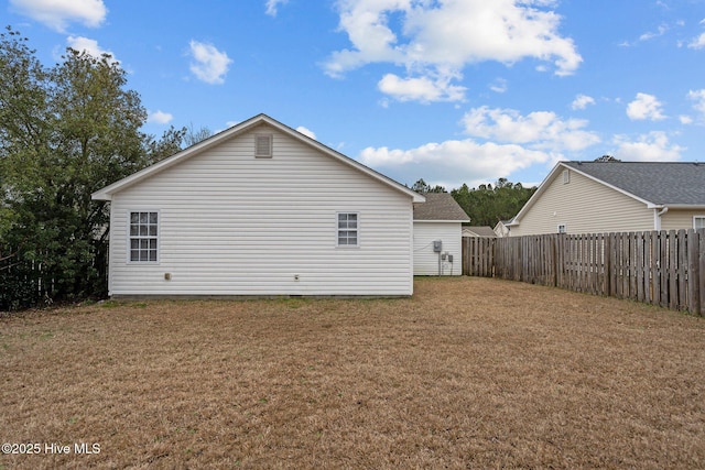 rear view of property featuring a yard and fence