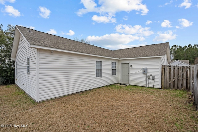 back of house featuring a shingled roof, fence, and a yard