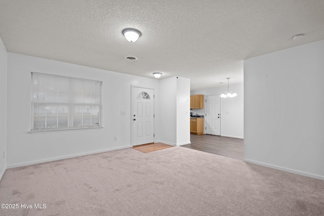 interior space with baseboards, a textured ceiling, visible vents, and an inviting chandelier