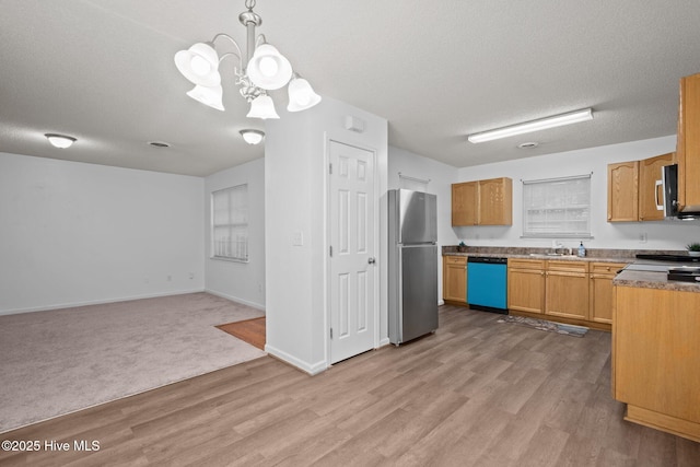 kitchen with stainless steel appliances, open floor plan, a textured ceiling, and light wood finished floors