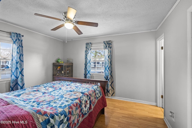 bedroom with a textured ceiling, baseboards, wood finished floors, and crown molding