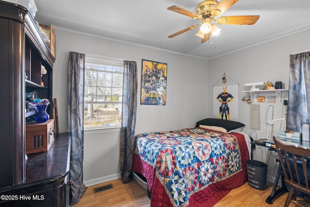 bedroom featuring a textured ceiling, ornamental molding, wood finished floors, and visible vents