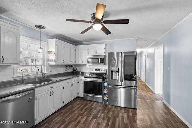 kitchen featuring stainless steel appliances, dark wood-style flooring, dark countertops, and a sink