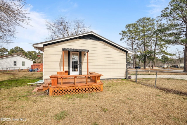 back of property with a yard, a wooden deck, and fence