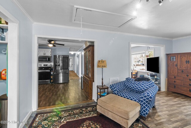 living area featuring dark wood-style floors, attic access, visible vents, and ornamental molding