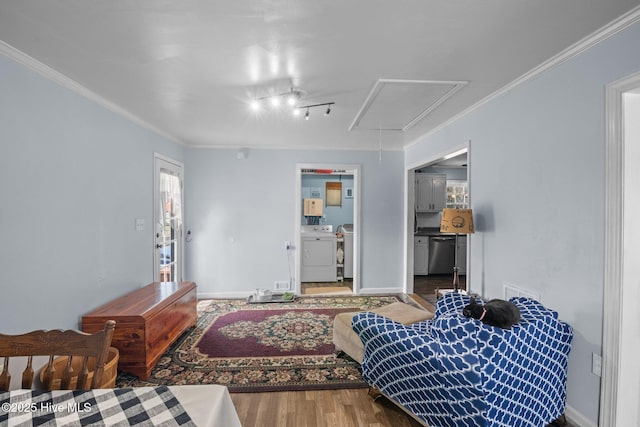 bedroom featuring washer / clothes dryer, wood finished floors, attic access, and crown molding