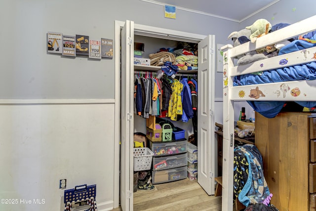 bedroom featuring ornamental molding, a closet, and wood finished floors