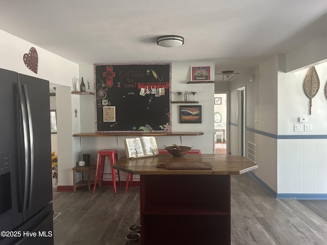 kitchen featuring black refrigerator with ice dispenser and wood finished floors