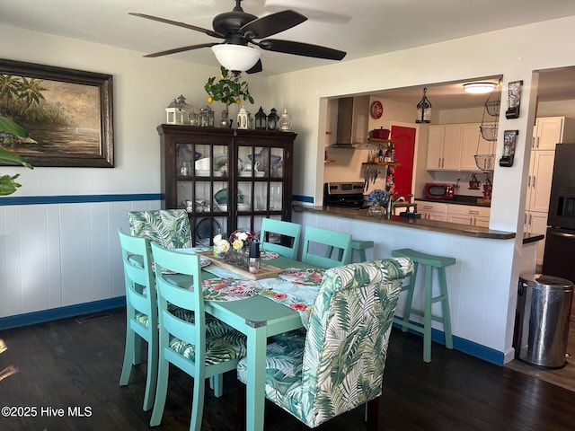 dining room featuring dark wood-type flooring, wainscoting, and a ceiling fan